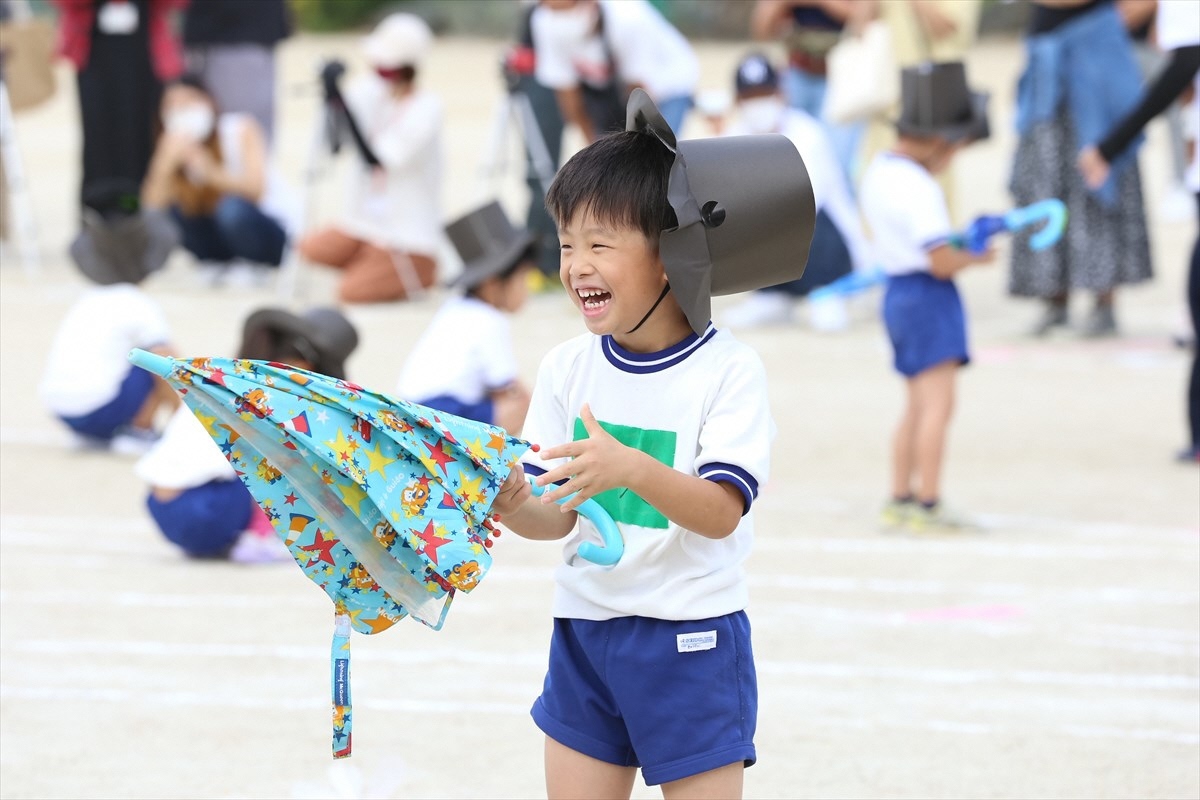 傘を持って笑顔で踊る男の子の写真