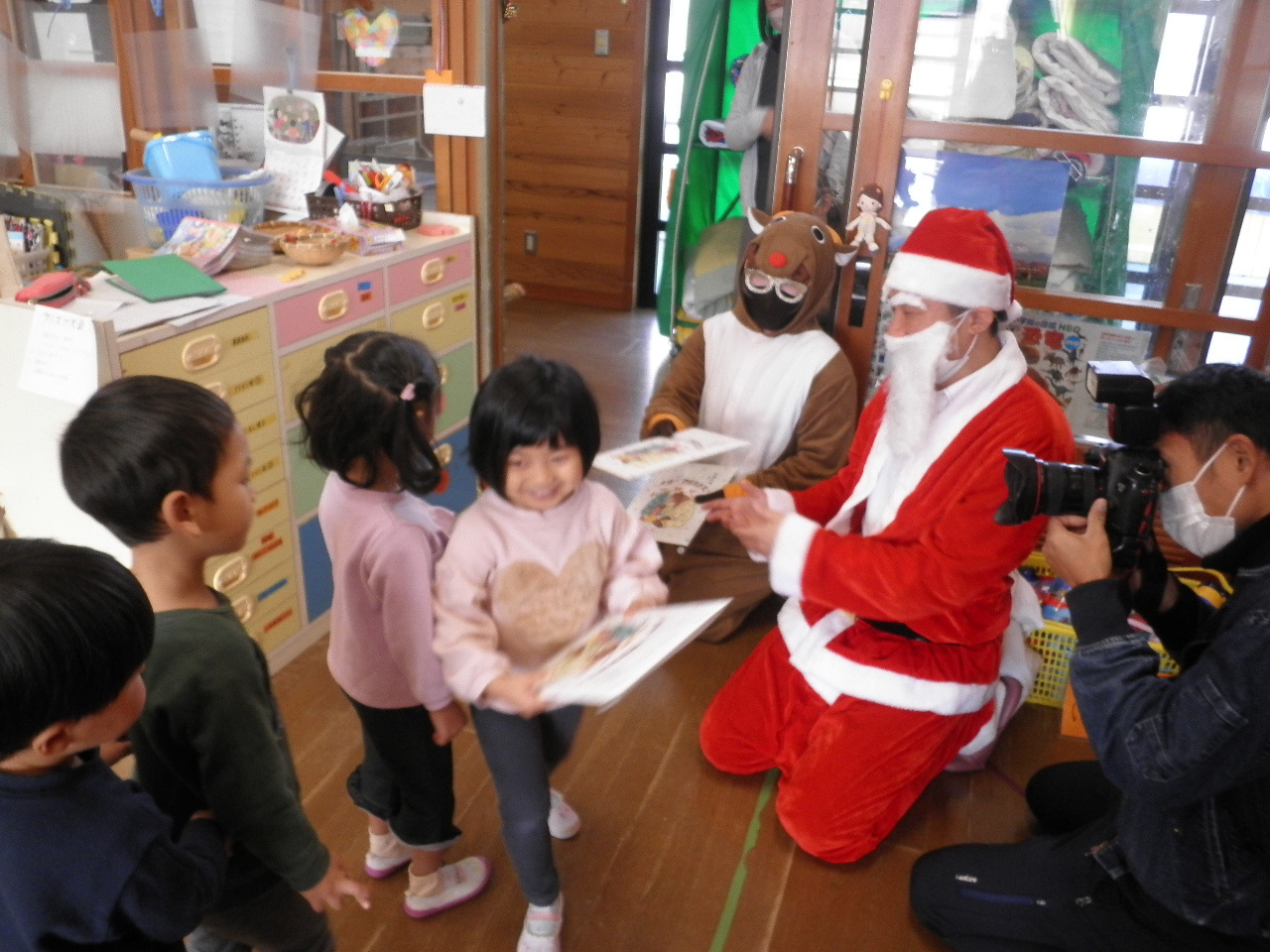 サンタクロースからプレゼントをもらっている子ども達の写真