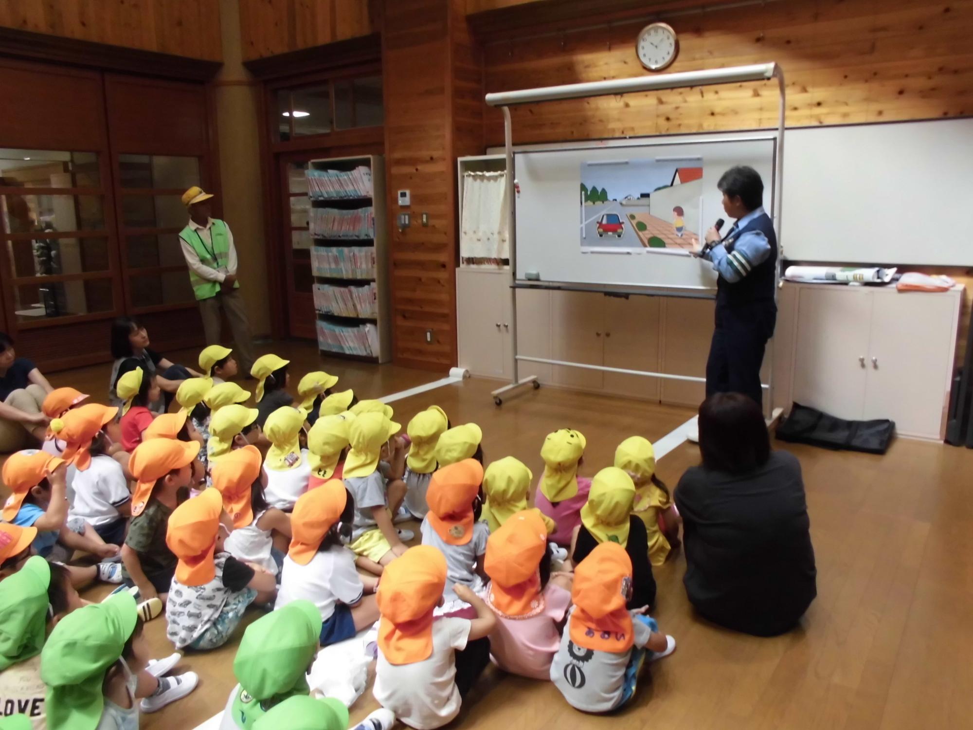 警察官が子どもたちにイラストを使って交通ルールについて話している様子の写真