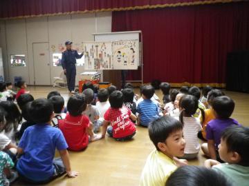 ホールに子ども達が集まって座っており、消防士さんの話を聞いてる写真