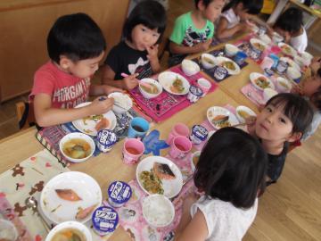 子ども達が席に着き、テーブルに並べられているご飯を食べている写真