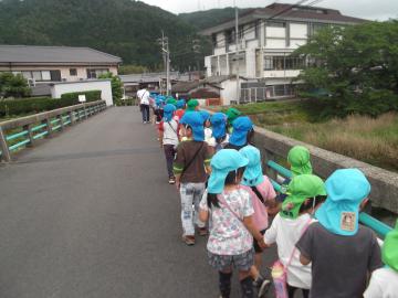 橋の上の右側を友達と手をつないで、列をつくりながら歩いている園児たちの写真