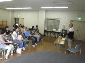 参加者親子が椅子に座って、岩城先生の講演の話を聞いている写真