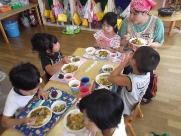 子ども達が椅子に座り、作ったカレーを食べている写真