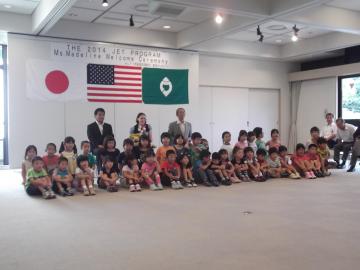 日本やアメリカの国旗の前に子供たちや関係者たちが並んでいる集合写真