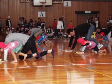 体育館で親子が雑巾がけ競争をしている写真