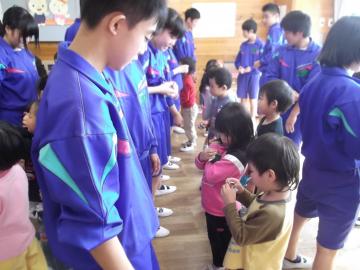 子ども達が向かい合った中学生から手作りのお手玉をもらっている写真