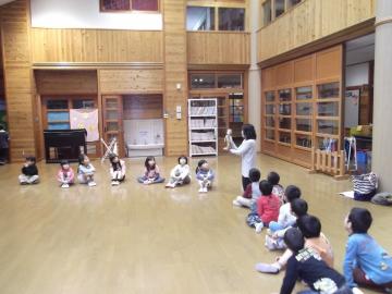 子ども達が円を囲むように座り、奥先生のわらべうたを見ている写真