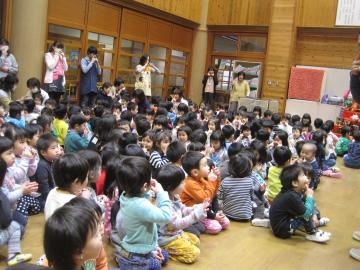 子どもたちが床に座って歌いながら手遊びをしている写真