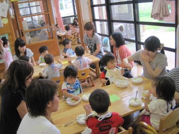 給食を食べている子どもたちとその様子を傍で見守る保護者の写真