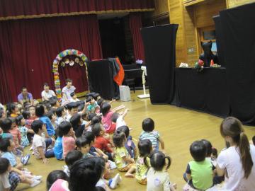 子どもたちがはらぺこあおむしの人形劇を見ている写真