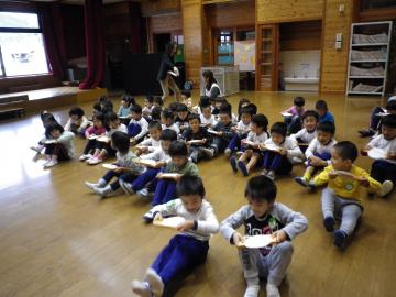 子どもたちが紙を膝から落とさず前進する遊びをしている写真