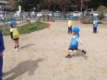 黄色のビブスと水色のビブスの子どもたちがサッカーをしている写真