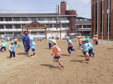 子どもたちがグラウンドを走り回りサッカーの試合をしている写真