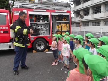 年中児に話をしている消防署員と消防車を見せてもらっている年中児の写真