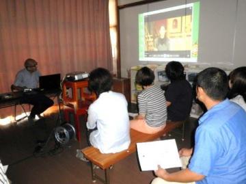 スクリーンに映し出された映像を見ながら話をしている岩城先生と岩城先生の講演を聴いている参加者の写真