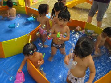 2歳児がプールの中でしゃぼん玉をしている写真
