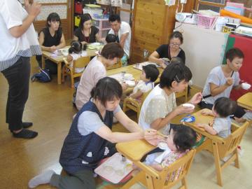 椅子に座った子どもたちに給食を食べさせている写真