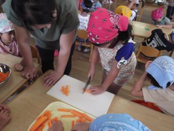 子どもたちが三角巾とエプロンをして野菜を切っている写真