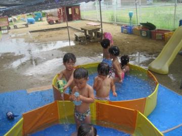 子どもがプールで玩具を使って遊んでいる写真