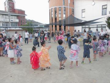 浴衣や甚平を着た子供たちが盆踊りをする様子の写真