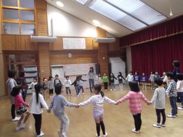 奥朗子先生のわらべうたの遊びで子どもたちが手をつないで輪になっている様子の写真