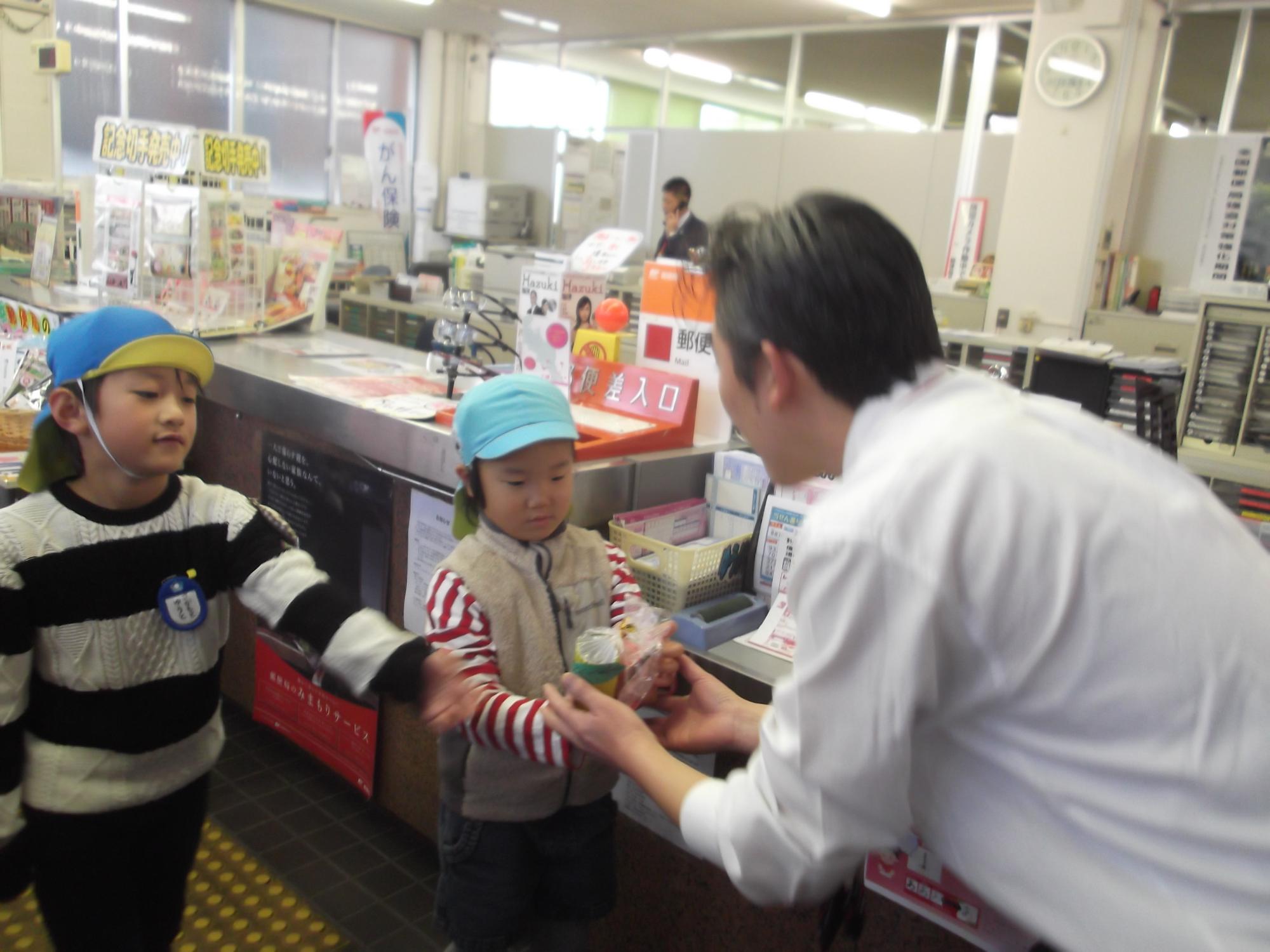 子どもたちが郵便局の方にプレゼントを渡している写真