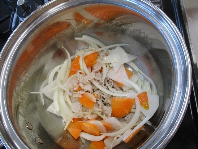 鍋で豚肉と野菜を炒めている写真