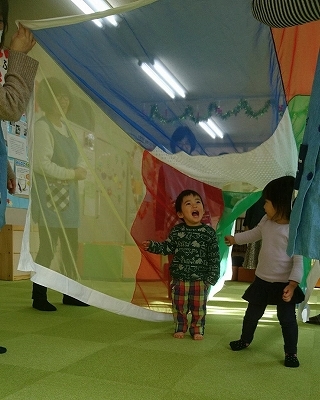 男の子と女の子がカラフルな布のトンネルをくぐり楽しそうな様子の写真