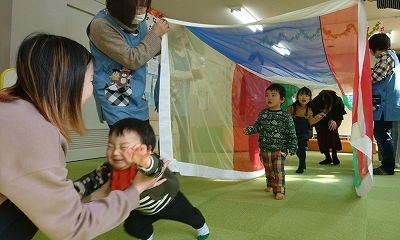 カラフルな布のトンネルをくぐる子ども達と、泣いて母親に駆け寄る男の子の写真