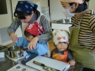 お母さんと子どもが一緒に鍋をかき混ぜている写真