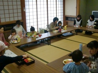 四角に囲んだ長テーブルに親子が座り料理を食べている写真
