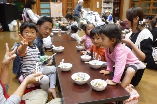 テーブルを挟んで座っている参加者の親子が、うどんを食べている写真