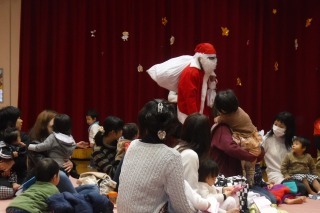 プレゼントの入った白い大きな袋を肩に背負って登場した、赤い服を着て、白いひげを生やしたサンタクロースの写真