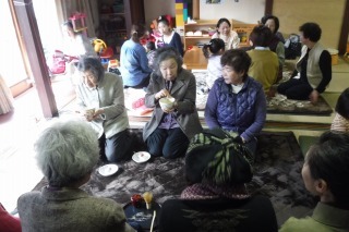 年配の女性たちが並んで座りお茶を飲んでいる写真