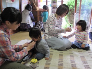 子どもによもぎ団子を食べさせている母親の写真