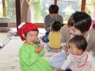 三角巾をつけた子どもがよもぎお団子を食べている写真