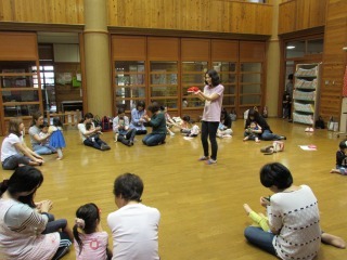 中央に立っている講師を円で囲むように参加者親子が座り、布で遊んでいる写真