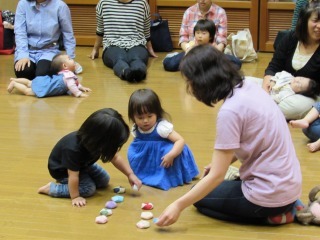 子どもが床に並んでいるおじゃみを手に取っている写真