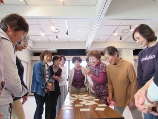 参加者が机の周りに集まりカードゲームをしている写真