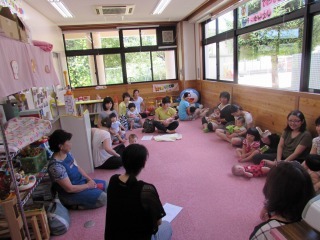 ピンクのカーペットの上で親子が円になって座り、家族の絆について話を聞いている写真