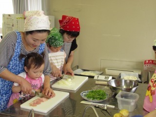 ママとこどもが包丁で野菜や、ベーコンを切っている写真