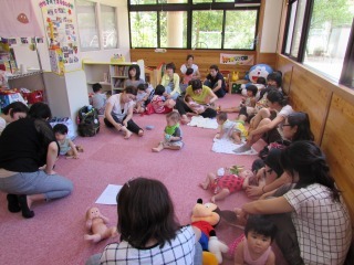 ピンクのカーペットの上で親子が円になって座り、三陰交のつぼを教えてもらっている写真