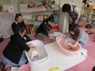 赤ちゃん人形をベビーバスにいれて沐浴指導を受けている参加者の写真
