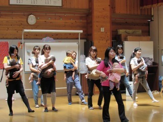 ママ達が赤ちゃんを抱っこしながらダンスをしている写真