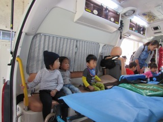 救急車の中の椅子に子ども達が座って救急車の中を見ている試乗の様子の写真