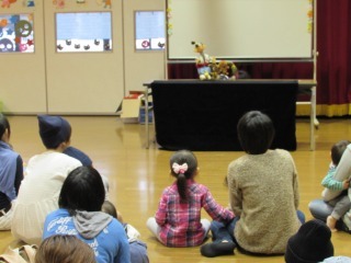桃太郎の人形劇を観ている親子の写真