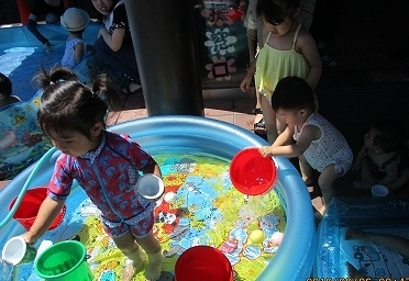 幼児らがビニールプールで遊んでいる写真