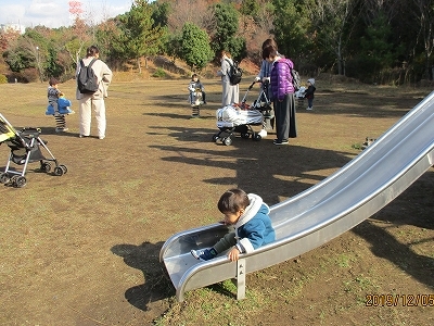 公園の滑り台を滑る子どもの写真