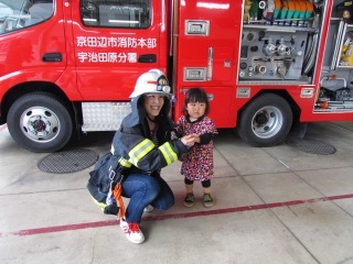 消防車の前で消防服を着たお母さんと子供の写真